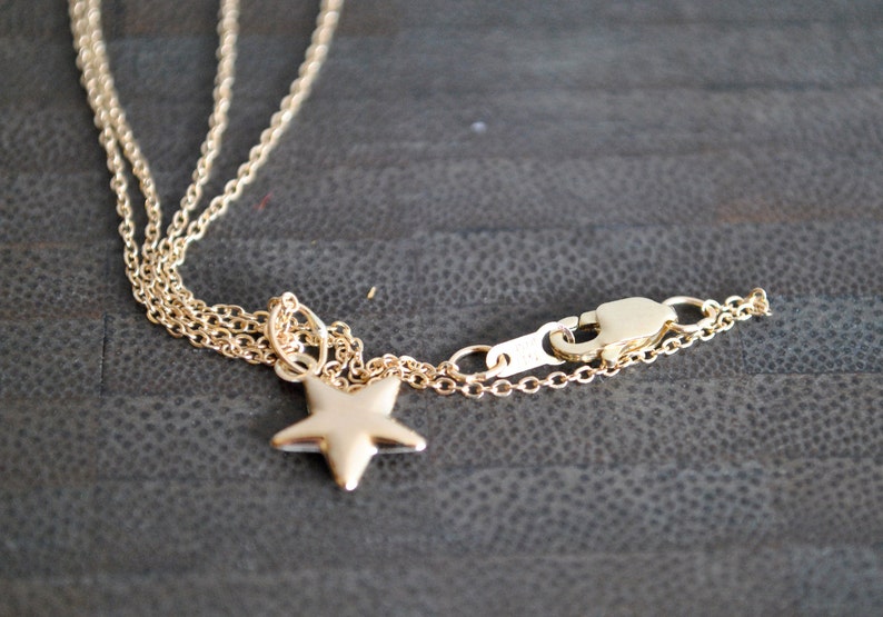 May include: A gold chain necklace with a star pendant and a lobster clasp closure.