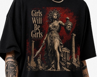 May include: A black t-shirt featuring a graphic print of a statue of Medusa holding a severed head and a sword. The design includes classical columns, a red textured background, and the text "Girls Will Be Girls" in a serif font on the left side.