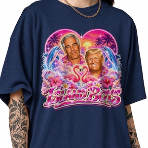 以下が含まれることがあります： ネイビーブルーのTシャツ。ジェフリー・エプスタインとドナルド・トランプの2人の男性、ピンクのフラミンゴ、イルカ、ヤシの木、夕日が描かれたグラフィックプリントが特徴。下部にはピンクのフォントで「ISLAND BOYS」という文字がプリントされている。