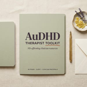 Può includere: Un taccuino verde salvia con il testo "AuDHD THERAPIST TOOLKIT" e "ND-affirming clinician resources". Una penna dorata, un piattino con semi gialli e una busta sono anche sulla superficie beige. Il taccuino ha 80 pagine di materiali per clienti e clinici.