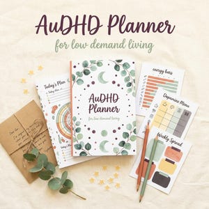 Może przedstawiać: Otwarty planer z napisem "AuDHD Planner for low demand living" jest otoczony dodatkowymi stronami do planowania, ołówkami i małą kopertą. Planer ma kwiatowy wzór z półksiężycem i kropkami.