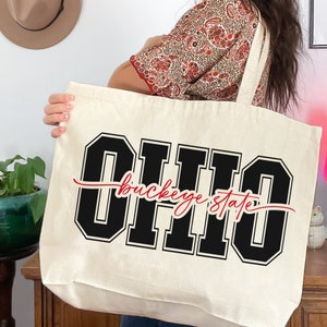 Digital design for crafting svg file for cricut silhouette print and cut clip art iron on transfer. Ohio is in an all capital double lined collegiate font. Sliced through the center in a red long tail cursive font it says buckeye state.