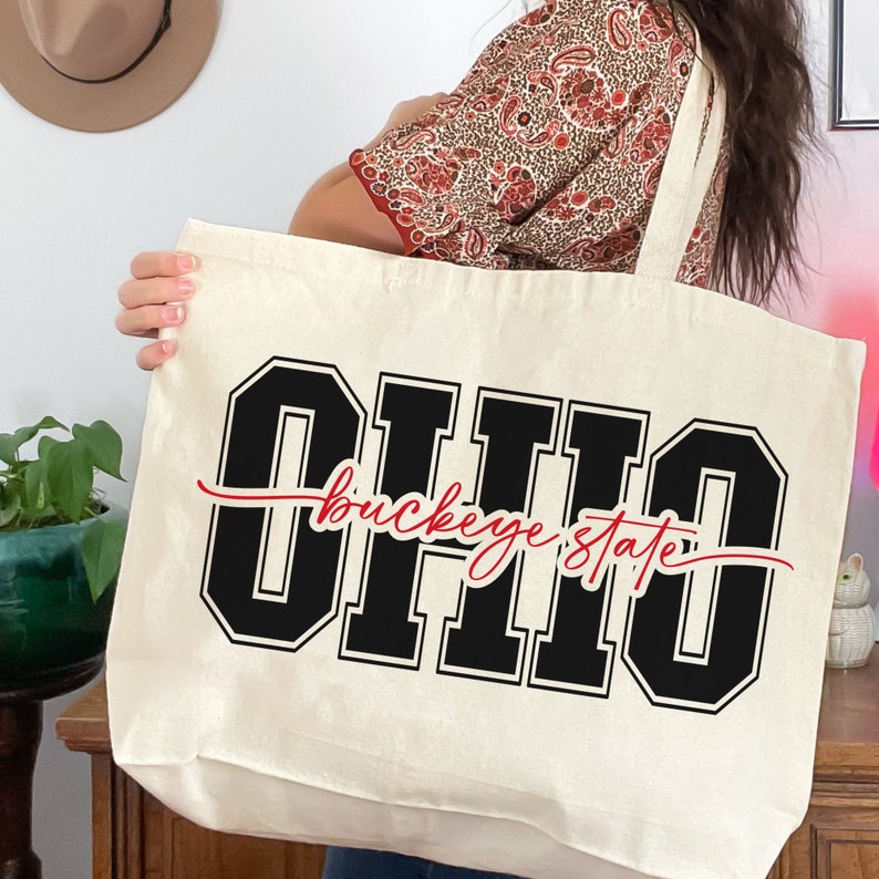 Digital design for crafting svg file for cricut silhouette print and cut clip art iron on transfer. Ohio is in an all capital double lined collegiate font. Sliced through the center in a red long tail cursive font it says buckeye state.