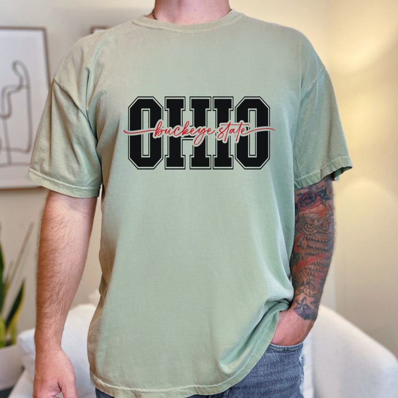 Digital design for crafting svg file for cricut silhouette print and cut clip art iron on transfer. Ohio is in an all capital double lined collegiate font. Sliced through the center in a red long tail cursive font it says buckeye state.