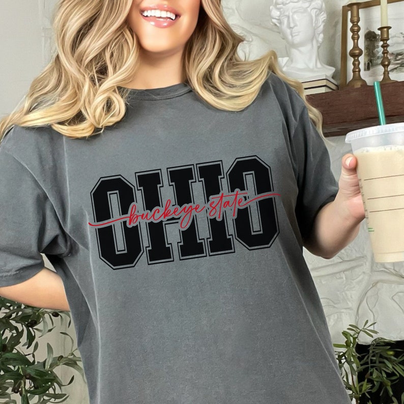 Digital design for crafting svg file for cricut silhouette print and cut clip art iron on transfer. Ohio is in an all capital double lined collegiate font. Sliced through the center in a red long tail cursive font it says buckeye state.