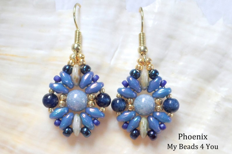 May include: A pair of drop earrings featuring a central light blue round bead surrounded by a geometric arrangement of dark blue, metallic blue, and gold-toned seed beads, suspended from gold-toned metal hooks. Text reads: Phoenix My Beads 4 You.