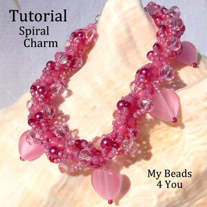 Op de afbeelding: Een handgemaakte roze kralenarmband met hartvormige bedels. De armband heeft een spiraalvormig ontwerp met verschillende tinten roze kralen en heldere kristallen accenten. De tekst op de afbeelding luidt "Tutorial Spiral Charm" en "My Beads 4 You".