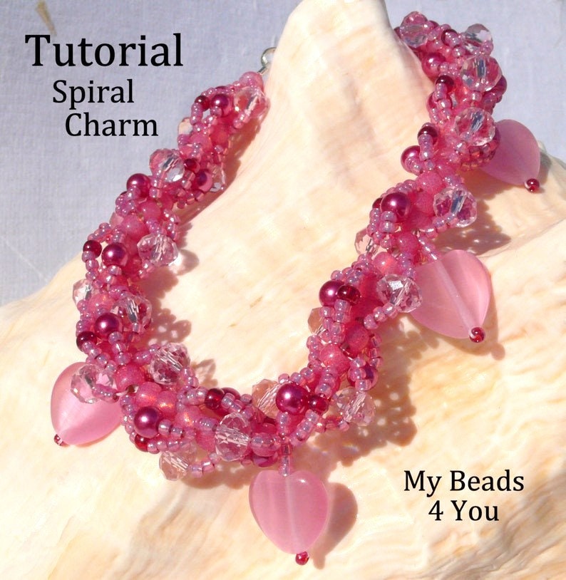 Op de afbeelding: Een handgemaakte roze kralenarmband met hartvormige bedels. De armband heeft een spiraalvormig ontwerp met verschillende tinten roze kralen en heldere kristallen accenten. De tekst op de afbeelding luidt "Tutorial Spiral Charm" en "My Beads 4 You".