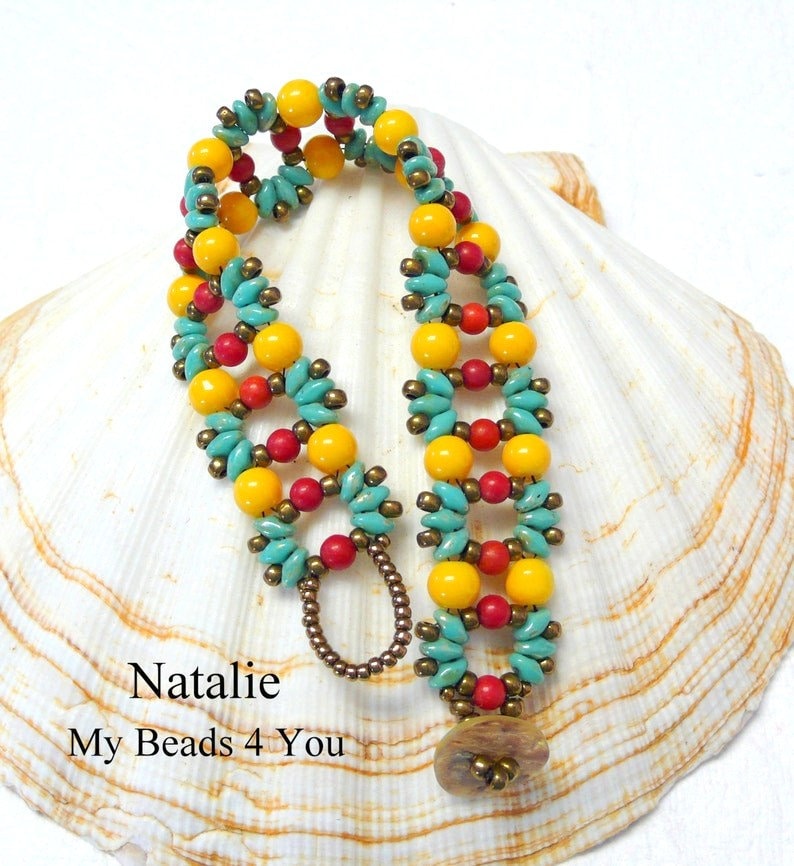 K&ouml;nnte beinhalten: Ein Armband mit gelben, t&uuml;rkisfarbenen und roten Perlen. Das Armband liegt auf einem wei&szlig;en Muschelhintergrund. Der Text "Natalie My Beads 4 You" ist unterhalb des Armbands sichtbar.