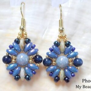 May include: A pair of dangle earrings featuring a central light blue round bead surrounded by a geometric pattern of dark blue, light blue, and metallic gold beads. The earrings hang from gold-toned metal hooks and include the text Phoenix My Beads 4 You.