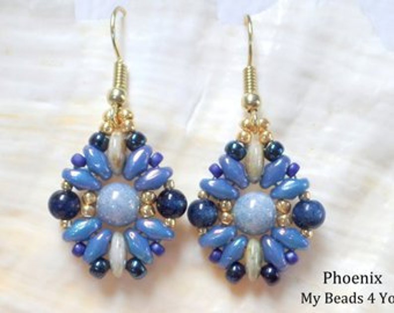 May include: A pair of dangle earrings featuring a central light blue round bead surrounded by a geometric pattern of dark blue, light blue, and metallic gold beads. The earrings hang from gold-toned metal hooks and include the text Phoenix My Beads 4 You.