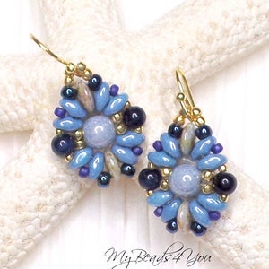 May include: A pair of drop earrings featuring a central light blue round bead surrounded by a floral pattern of elongated light blue, dark blue, and purple beads, accented with small gold metallic beads and gold-toned ear wires.