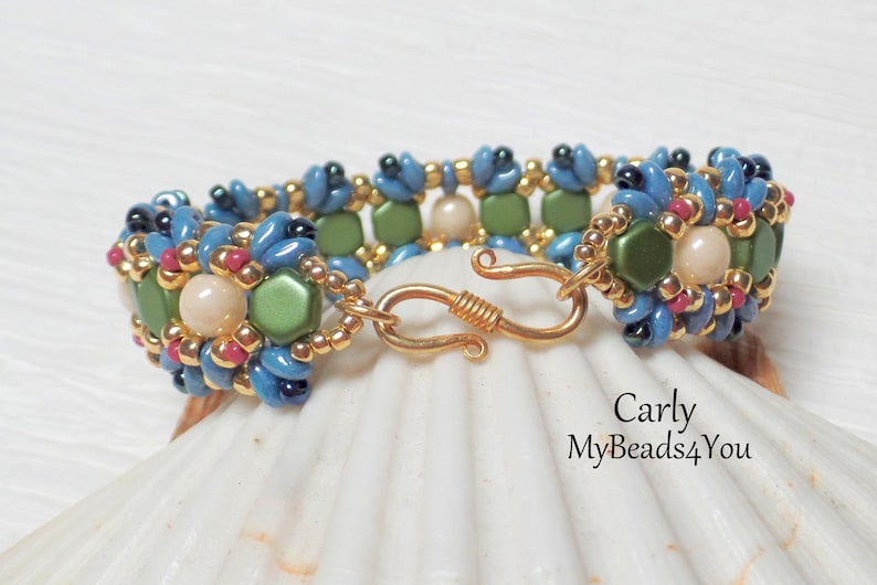 May include: A beaded bracelet with a floral design. The bracelet features blue, green, pink, and gold beads. The clasp is gold-colored. The bracelet is approximately 7 inches (17.78 cm) in length. The text "Carly MyBeads4You" is visible.
