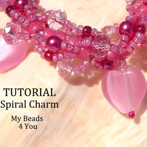 Op de afbeelding: Een close-up van een spiraalvormige bedeltutorial. De bedel is gemaakt van roze kralen en heeft twee hartvormige hangers. De tekst "TUTORIAL Spiral Charm My Beads 4 You" is zichtbaar.