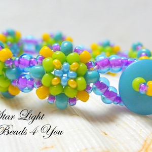 Peut inclure: Un bracelet en perles avec une fermeture bouton turquoise. Le bracelet est fait de petites perles color&eacute;es dans des tons de jaune, vert, bleu et violet. Les perles sont dispos&eacute;es en forme de fleur. Le bracelet est sur un fond blanc.