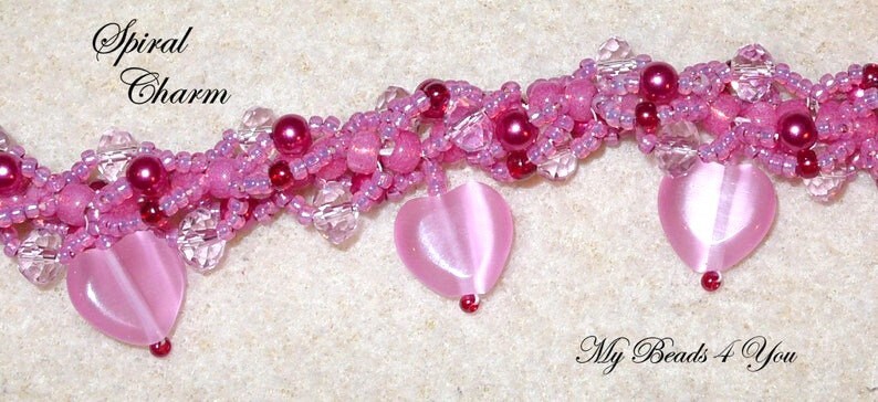 Op de afbeelding: Een roze kralen bedelarmband met hartvormige hangers. De armband heeft een spiraalvormig ontwerp met verschillende roze tinten, heldere kristallen en donkerroze accenten. De tekst "Spiral Charm" is zichtbaar.