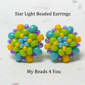 Peut inclure: Boucles d'oreilles en perles Star Light, une paire de petites boucles d'oreilles color&eacute;es avec des perles turquoise, vertes, jaunes et violettes. Les boucles d'oreilles ont la forme d'une fleur.