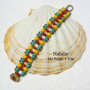 K&ouml;nnte beinhalten: Ein Armband mit gelben, roten und t&uuml;rkisfarbenen Perlen. Das Armband liegt auf einer wei&szlig;en Muschel mit dem Text "Natalie My Beads 4 You".