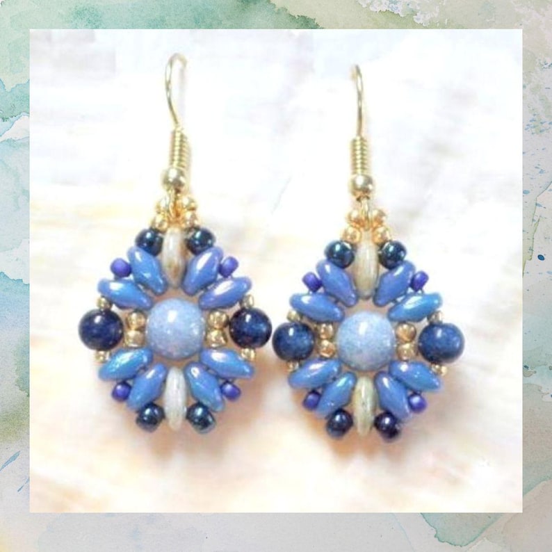 May include: A pair of dangle earrings featuring a central light blue round bead surrounded by a geometric pattern of smaller blue, dark blue, and metallic gold beads. The earrings are suspended from gold-toned metal hooks for pierced ears.