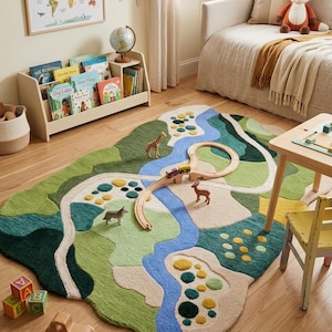 May include: A children's rug with a landscape design featuring a river, hills, and roads. Wooden toy train tracks, a giraffe, a deer, and a dog are placed on the rug. The room also includes a bookshelf, a world map, and a small table. The rug's design is reminiscent of a map.