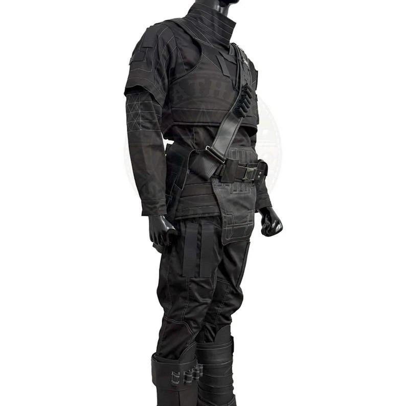 May include: A black tactical outfit consisting of a long-sleeved shirt with reinforced stitching, a structured chest plate, and matching trousers. The ensemble includes a utility belt, a diagonal shoulder strap with loops, and tall boots.