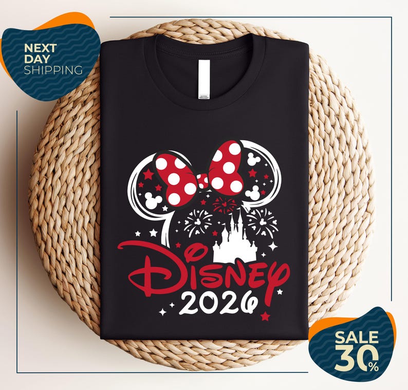 A black t-shirt with a Disney-themed design, including a pair of Mickey Mouse ears, fireworks, and the text "Disney 2020". The t-shirt is displayed on a woven placemat, and there are two sale signs indicating a 30% discount.