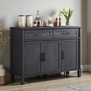 May include: A dark gray wooden sideboard with two drawers and three cabinet doors. The top surface displays decorative items, including jars, bottles, and a vase of flowers. The text "Serena Nest" is visible on the front.