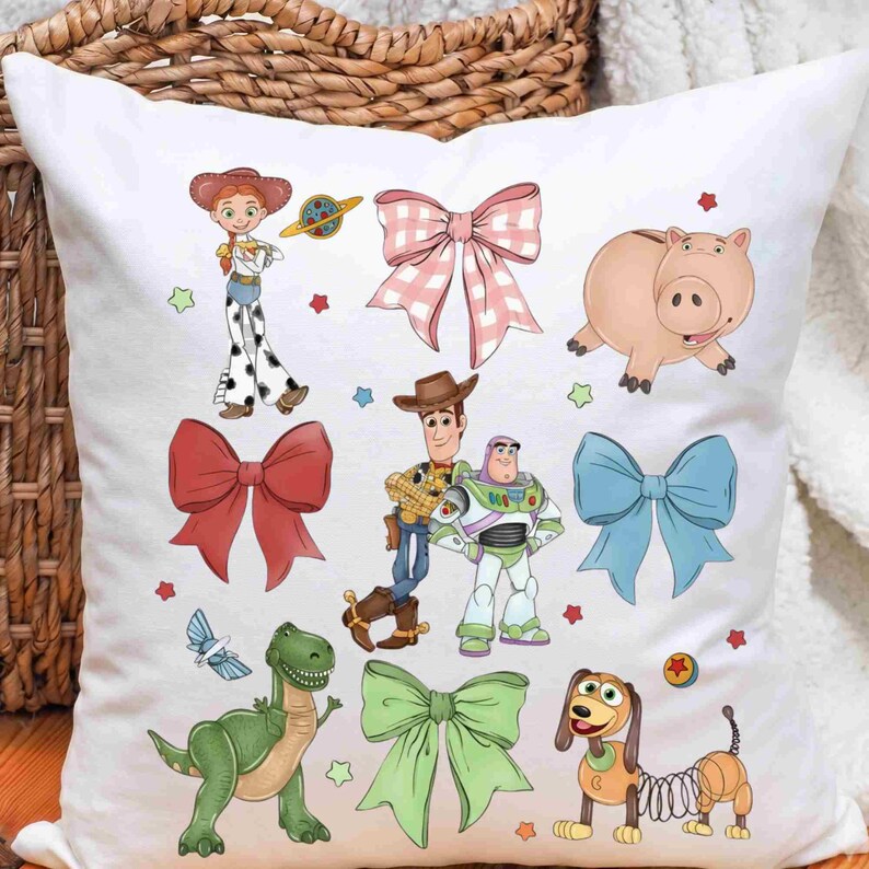 May include: A white square throw pillow featuring a colorful print of Toy Story characters including Jessie, Woody, Buzz Lightyear, Hamm, Rex, and Slinky Dog, interspersed with various solid-colored bows and a pink gingham bow pattern.