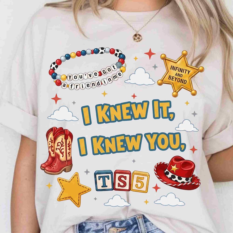 May include: A white t-shirt featuring a graphic print with a beaded bracelet reading 'You've got a friend in me', a gold sheriff star badge with 'INFINITY AND BEYOND', red cowboy boots, a red cowboy hat, and blocks spelling 'TS5'. Text reads 'I KNEW IT, I KNEW YOU'.