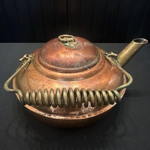 Tetera de cobre y latón con asa en espiral.