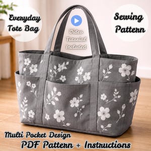 Könnte beinhalten: Eine graue Tragetasche mit weißem Blumenmuster, ausgestattet mit zwei Tragegriffen und mehreren Außentaschen. Der Text auf dem Bild lautet Everyday Tote Bag, Sewing Pattern, Video Tutorial Included, Multi Pocket Design, PDF Pattern + Instructions.