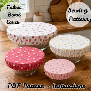 May include: Four fabric bowl covers in varying sizes and patterns, including a white strawberry print, a white lemon print, a red apple print, and a pink floral print. Each cover features an elasticized edge designed to fit over glass bowls.