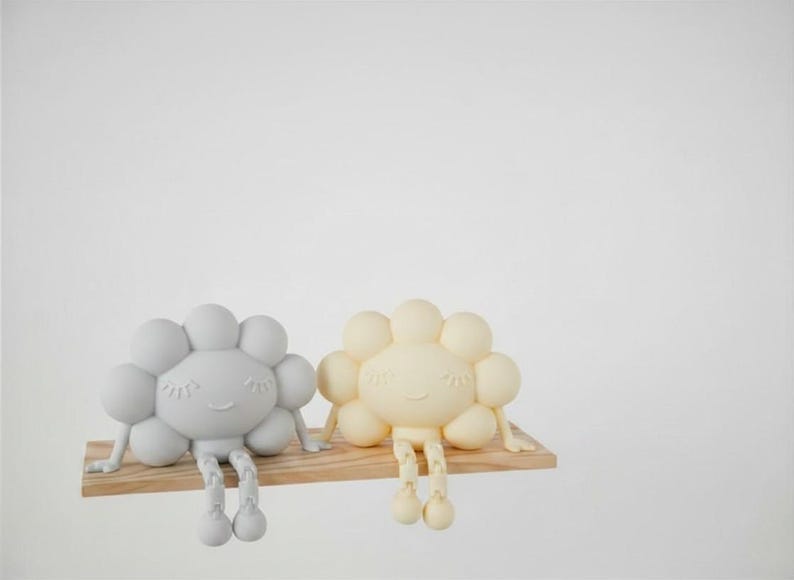 K&ouml;nnte beinhalten: Zwei skurrile, wolkenf&ouml;rmige Figuren in Hellgrau und Creme, jeweils mit einem l&auml;chelnden Gesicht und h&auml;ngenden Beinen, sitzen auf einem kleinen Holzregal. Die Figuren haben ein verspieltes Design, perfekt f&uuml;r die Kinderzimmerdekoration.