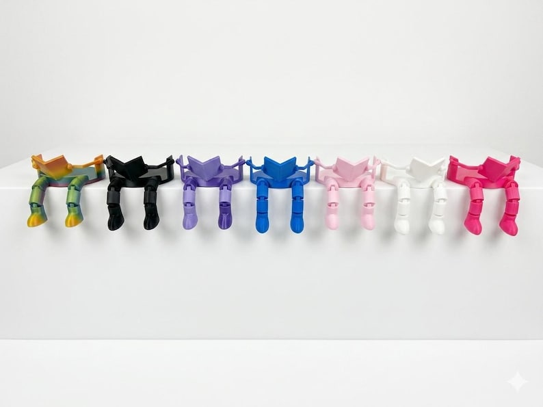 May include: A collection of colourful bookends, each designed as a person reading. The bookends are in a range of colours: rainbow, black, purple, blue, pink, white, and red. They are arranged on a white surface.