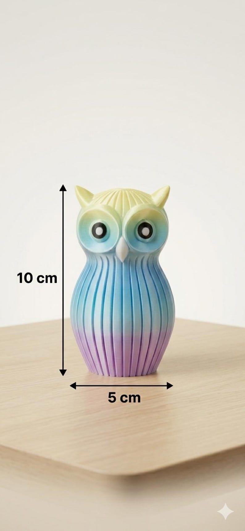 Puede incluir: Figura de b&uacute;ho colorida, de aproximadamente 5 cm de ancho y 10 cm de alto, con un degradado de amarillo, azul y morado. El b&uacute;ho tiene ojos grandes y negros y est&aacute; hecho de un material acanalado. Un art&iacute;culo decorativo.
