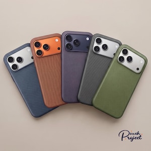 Op de afbeelding: Vijf smartphonehoesjes in een waaier gerangschikt, met getextureerde achterpanelen in blauw, oranje, paars, donkergrijs en olijfgroen. Elk hoesje heeft een rechthoekige cameramodule met drie ronde lenzen en een flitser, met de tekst Douch Project.
