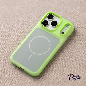 Pu&ograve; includere: Una custodia per telefono verde lime con retro trasparente e design circolare bianco. La custodia ha un bordo rialzato attorno agli obiettivi della fotocamera e un bordo verde abbinato. La custodia &egrave; progettata per uno smartphone.