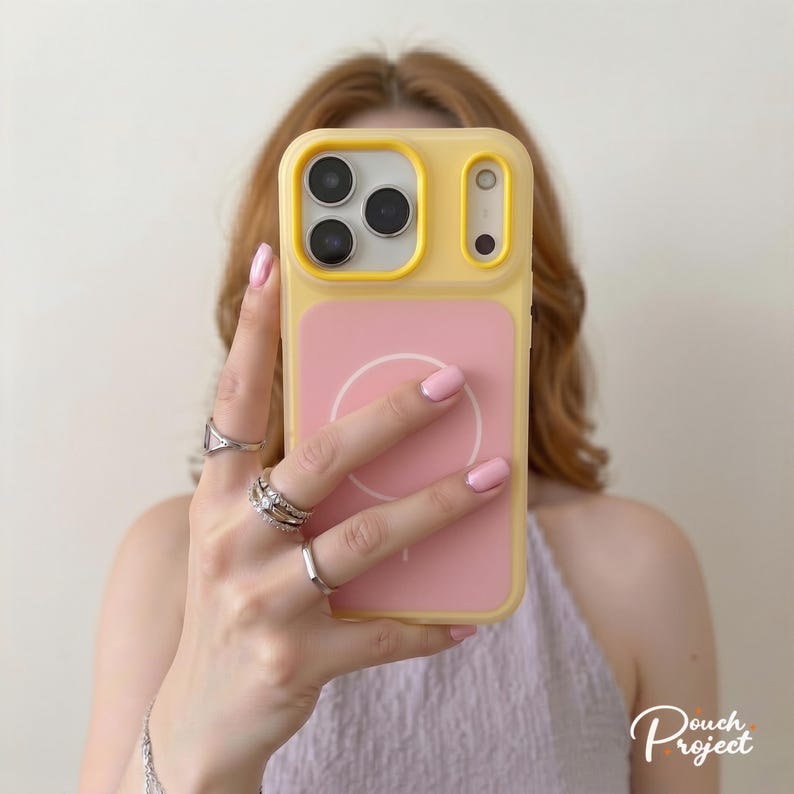 Pu&ograve; includere: Una custodia per telefono gialla e rosa con design MagSafe. La custodia ha un bordo giallo e un retro rosa con un cerchio bianco. La custodia del telefono &egrave; tenuta davanti a una persona.