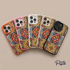 May include: Five smartphone cases arranged in a fan shape, each featuring a colourful tile pattern with red, blue, yellow, and green floral motifs. The cases have distinct coloured borders in orange, pink, white, beige, and black, with camera cutouts.