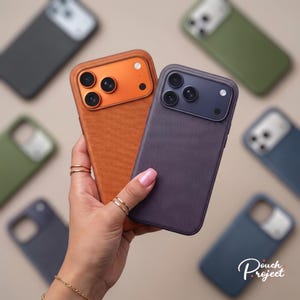 May include: Two smartphone cases with textured backs and camera cutouts, one in bright orange and one in dark purple, held together. Additional cases in olive green, dark blue, and black are arranged in the background with the text Pouch Project.