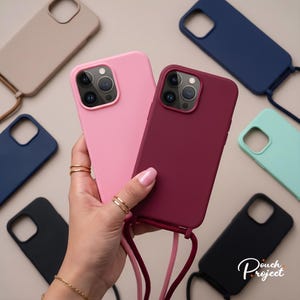 Op de afbeelding: Een collectie siliconen smartphonehoesjes met bevestigde crossbody-koorden in diverse effen kleuren, waaronder roze, bordeauxrood, marineblauw, zwart, beige en mintgroen. Elk hoesje is voorzien van een vierkante uitsparing voor de camera.