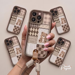 Può includere: Cinque cover per telefono marroni e beige con un design patchwork di motivi a quadri, rombi e maglia a trecce. Ogni cover presenta un'illustrazione di un orsetto e piccoli volti di orso. Una cover include un cinturino da polso marrone.