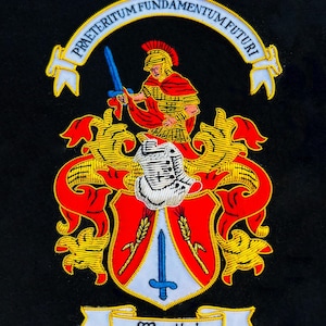 May include: Embroidered crest on black fabric. The crest features a Roman soldier with a sword, a shield, and the text "PRAETERITUM FUNDAMENTUM FUTURI". The word "Martini" is displayed on a banner below the shield.