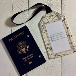 May include: A blue passport with the words "PASSPORT" and "United States of America" printed on the cover. A white luggage tag with a map design and black text is attached to a black strap.