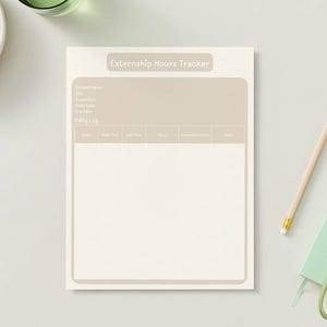 May include: A cream-colored "Externship Hours Tracker" notepad with a light brown header and a daily log section. A pencil, a small green notebook, and a set of keys are next to the notepad. A bowl of green grapes is in the upper left corner.