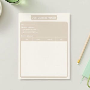 May include: A beige Daily Caseload Planner with a brown header and sections for Caseload Overview and Session Schedule. A pencil, a small green notebook, and a bunch of grapes are also visible.