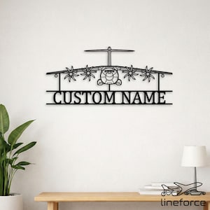 May include: A black metal wall art piece shaped like a four-engine cargo aircraft with a T-tail design. Below the aircraft silhouette, a horizontal bar features the text CUSTOM NAME in a bold, sans-serif font, creating a cohesive display.