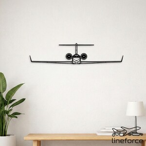 Puede incluir: Arte de pared de avión de metal negro. La obra de arte representa un avión visto de frente, con alas y motores detallados. Montado en una pared blanca, crea un contraste llamativo. El diseño es minimalista y moderno, adecuado para entusiastas de la aviación.