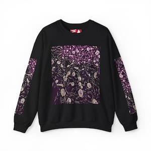 Könnte beinhalten: Schwarzes Sweatshirt mit Rundhalsausschnitt und einem abstrakten lila-weißen Design auf der Vorderseite und den Ärmeln. Das Design zeigt wirbelnde Muster und kreisförmige Formen. Ein kleines rot-weißes Logo ist oben rechts sichtbar.