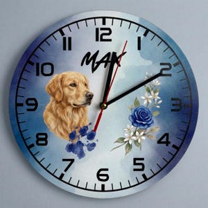 Może przedstawiać: Okrągły zegar ścienny z jasnoniebieskim akwarelowym tłem, przedstawiający portret golden retrievera, niebieską różę, białe kwiaty i niebieski odcisk łapy. Imię MAX jest nadrukowane na czarno nad psem, z czarnymi cyframi i wskazówkami zegara.